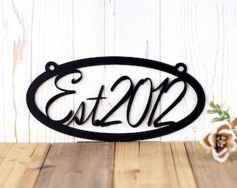 May include: Black metal oval sign with the text "Est 2012" in a cursive font.