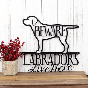 May include: Black metal sign with a silhouette of a Labrador Retriever and the text "Beware Labradors Live Here".
