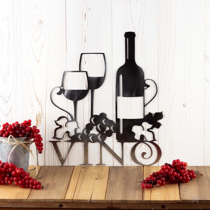 Vino metal plaque with wine glasses, bottle, and grapes, in raw steel. Placed against a wood wall.
