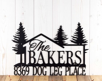 May include: Black metal house-shaped sign with two pine trees on either side. The sign reads "The Bakers 8369 Dog Leg Place".