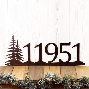 May include: Metal house number sign with the number 11951 and a silhouette of two pine trees on the left side. The sign is brown and has a rustic look.