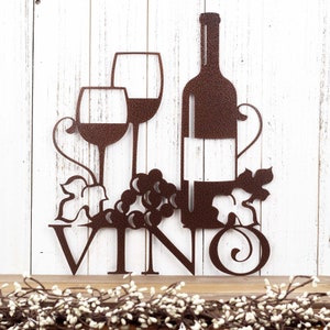 Vino metal sign with wine glasses, bottle, and grapes, in copper vein powder coat. Placed against a white wood wall.