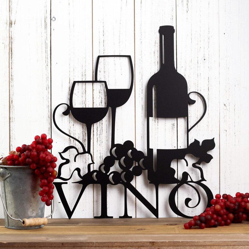Vino metal wall decor with wine glasses, bottle, and grapes, in matte black powder coat. Placed against a white wood wall.