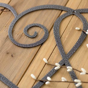 Close up of silver vein powder coat on our curly hearts metal sign.