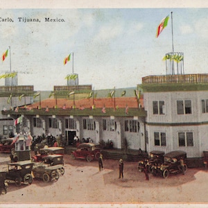 Puede incluir: Una taza de cerámica blanca con un asa negra y el texto "But First, Coffee" en negro, con una fuente de estilo manuscrito. La taza está sobre una superficie blanca.