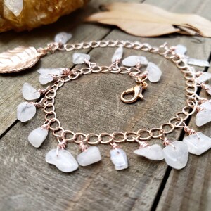 May include: A rose gold chain bracelet with a leaf charm and dangling moonstone chips.