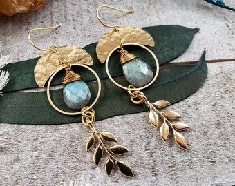 Peut inclure: Boucles d'oreilles en or avec une forme de croissant de lune et un cercle avec une pierre de labradorite bleu-vert. Les boucles d'oreilles ont un pendentif en feuille d'or.