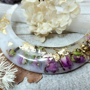 May include: A white crescent moon-shaped resin dish with dried flowers and gold leaf accents.