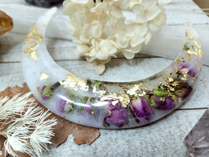 May include: A white crescent moon-shaped resin dish with dried flowers and gold leaf accents.