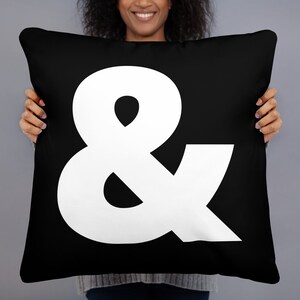 May include: Black and white throw pillow with a large white ampersand symbol in the center.