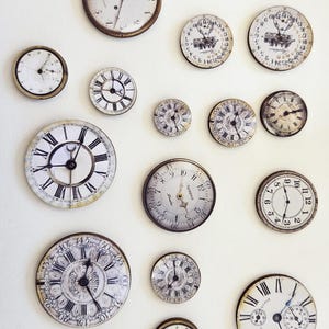 Peut inclure: Une collection de cadrans d'horloge anciens de différentes tailles et designs, disposés sur un fond blanc. Les horloges présentent des chiffres romains, des aiguilles ornées et des détails vieillis, évoquant une esthétique vintage. Un trombone argenté est également visible.