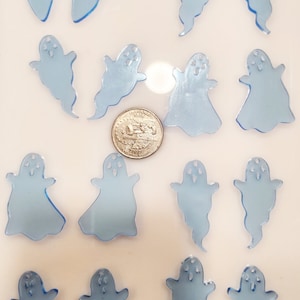 Może przedstawiać: Kolekcja 16 jasnoniebieskich, akrylowych zawieszek w kształcie ducha. Zawieszki są mniej więcej wielkości amerykańskiej monety 25 centów.