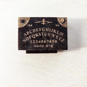 May include: A set of three ceramic mugs with a speckled, matte finish. The mugs are in shades of cream, light gray, and dark gray. Each mug has a simple, modern design and a rounded handle. The mugs are likely for coffee or tea.