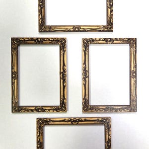 May include: Four rectangular picture frames with an ornate, raised relief pattern in a metallic gold and dark brown finish. Two frames are oriented horizontally and two frames are oriented vertically, all featuring intricate scrollwork details.