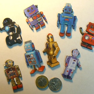 May include: A collection of eight vintage robot figurines, each with a unique design and color scheme. The robots are made of metal and have a retro look. They are all standing on a white surface.