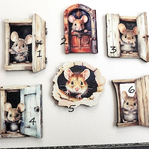 Könnte beinhalten: Sechs hölzerne Mäuse-Türschmuckstücke mit verschiedenen Designs. Jedes Ornament zeigt eine süße Maus, die aus einer Tür oder einem Loch schaut. Die Türen sind in verschiedenen Farben bemalt, darunter Braun, Blau und Weiß. Die Mäuse sind alle braun und weiß.