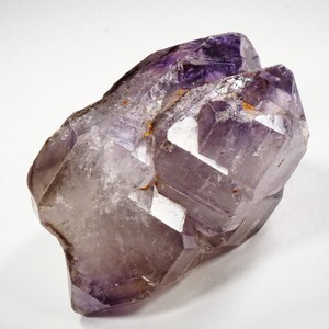 May include: A large, purple amethyst crystal with a clear, glassy appearance. The crystal has a double-terminated point and is naturally formed with multiple facets.