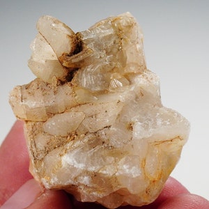 May include: A cluster of clear, translucent quartz crystals with a light brown hue. The crystals are clustered together in a rough, natural formation.