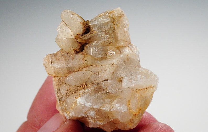 May include: A cluster of clear, translucent quartz crystals with a light brown hue. The crystals are clustered together in a rough, natural formation.