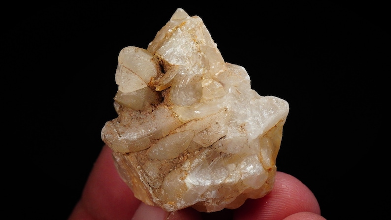 May include: A cluster of clear quartz crystals with a milky white hue. The crystals are clustered together in a rough, natural formation. The crystals have a translucent appearance and are slightly frosted.
