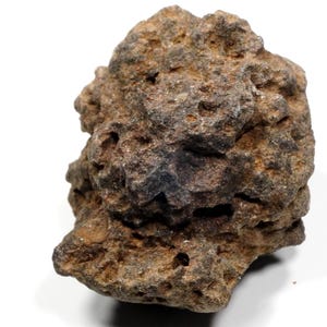 Könnte beinhalten: Ein rauer, poröser Stein mit unregelmäßiger, gezackter Form. Die Oberfläche ist mit zahlreichen kleinen Vertiefungen, Rissen und Erhebungen strukturiert und zeigt eine abwechslungsreiche Farbpalette aus erdigen Braun-, Beige- und Anthrazittönen.