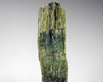 May include: A large, green, and black, rough, natural, mineral specimen. The mineral has a striated, layered, and textured surface.