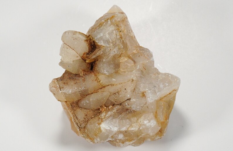 May include: A cluster of clear quartz crystals with a light brown tint. The crystals are clustered together in a rough, natural formation.