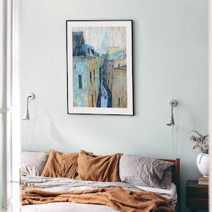 May include: A bedroom with a bed with brown and gray bedding and a framed painting of a city skyline with a church in the background. The painting is hanging on a light blue wall. There are two wall sconces on either side of the painting.