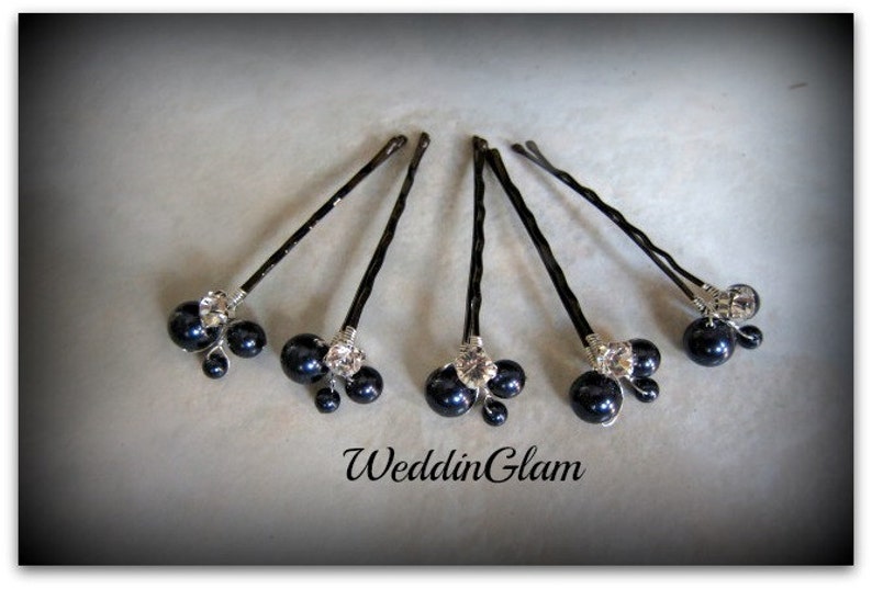 May include: Six black hair pins with a cluster of three black pearls and a rhinestone on each pin.