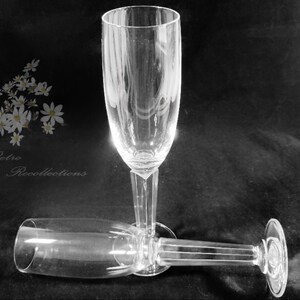 May include: Two clear champagne flutes, one upright and one lying down, against a dark background. The flutes have a tall, slender design with etched details. The image includes the text "Retro Recollections".