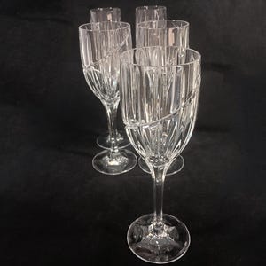 Vintage Mikasa Uptown clear heavy cut crytal stemware. This 5 piece set consists of three 9 inch water goblets and two 9 1/2 inch fluted champagne glasses. The bowls are vertically cut and polished from the rim to the stem and one horizontal spiral around the bowl. The tall slender stems are six-sided and curver gracerully into thesix-segmented foot.