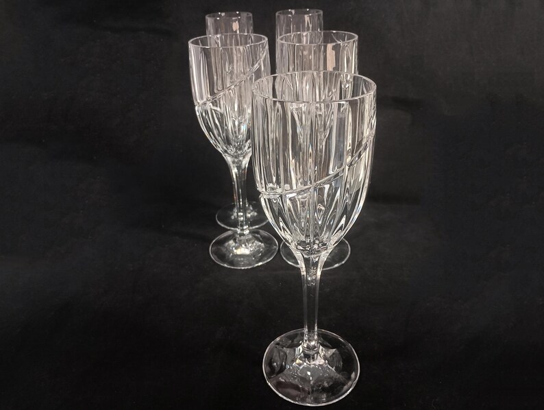 Vintage Mikasa Uptown clear heavy cut crytal stemware. This 5 piece set consists of three 9 inch water goblets and two 9 1/2 inch fluted champagne glasses. The bowls are vertically cut and polished from the rim to the stem and one horizontal spiral around the bowl. The tall slender stems are six-sided and curver gracerully into thesix-segmented foot.