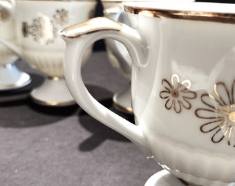 Mid Century Fancy White Porcelain Footed Coffee Mugs with delicate gold line daisies and metallic gold trim.