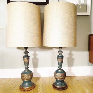May include: A pair of vintage lamps with blue and gold bases and beige linen shades. The lamps have a unique, ornate design.