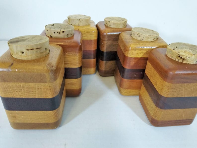 Mid Century Turned Stacked Layered Wood Spice Containers with Cork Stoppers. Set of 6 wooden spice jars  made of Layers of various varieties of dark and light colored wood stacked together, turned, and finished to warm rich layers of natural wood.