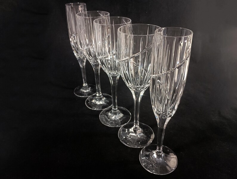Vintage Mikasa Uptown clear heavy cut crytal stemware. This 5 piece set consists of three 9 inch water goblets and two 9 1/2 inch fluted champagne glasses. The bowls are vertically cut and polished from the rim to the stem and one horizontal spiral around the bowl. The tall slender stems are six-sided and curver gracerully into thesix-segmented foot.