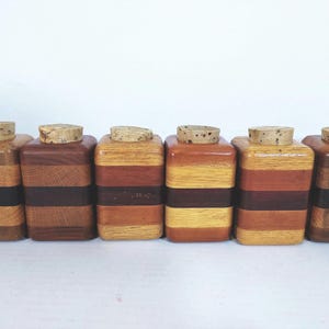 Mid Century Turned Stacked Layered Wood Spice Containers with Cork Stoppers. Set of 6 wooden spice jars  ade of Layers of various varieties of dark and light colored wood stacked together, turned, and finished to warm rich layers of natural wood.