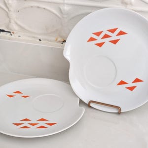 Pair or Jonas Roberts Japan snack plates with a white yin yang shape with orange diamonds on a white background and around indent to hold a cup or perhaps a little bowl of dipping sauce.