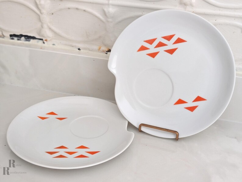 Pair or Jonas Roberts Japan snack plates with a white yin yang shape with orange diamonds on a white background and around indent to hold a cup or perhaps a little bowl of dipping sauce.