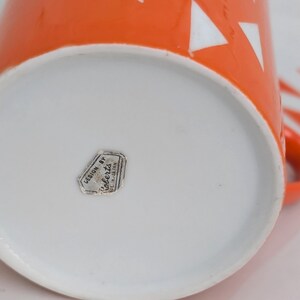 Jonas Roberts Japan snack set with white yin yang snack plate with orangediamonds and orange cup with white diamond pattern and remnants for the original silver Foil "Designed by Jonus Robers" label