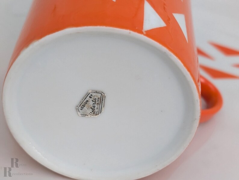 Jonas Roberts Japan snack set with white yin yang snack plate with orangediamonds and orange cup with white diamond pattern and remnants for the original silver Foil "Designed by Jonus Robers" label