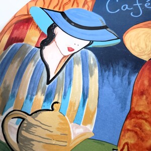 Furio Café plates displayed together: a large oval dinner plate featuring two women seated at a café table with a yellow teapot and cups, with bold, colorful artwork