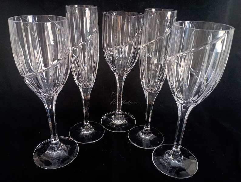 Vintage Mikasa Uptown clear heavy cut crytal stemware. This 5 piece set consists of three 9 inch water goblets and two 9 1/2 inch fluted champagne glasses. The bowls are vertically cut and polished from the rim to the stem and one horizontal spiral around the bowl. The tall slender stems are six-sided and curver gracerully into thesix-segmented foot.