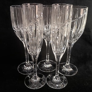 Vintage Mikasa Uptown clear heavy cut crytal stemware. This 5 piece set consists of three 9 inch water goblets and two 9 1/2 inch fluted champagne glasses. The bowls are vertically cut and polished from the rim to the stem and one horizontal spiral around the bowl. The tall slender stems are six-sided and curver gracerully into thesix-segmented foot.