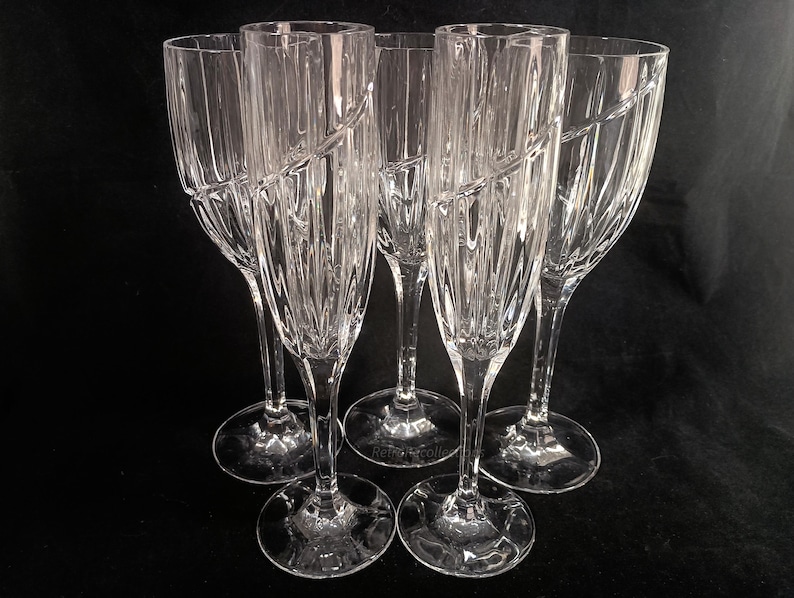 Vintage Mikasa Uptown clear heavy cut crytal stemware. This 5 piece set consists of three 9 inch water goblets and two 9 1/2 inch fluted champagne glasses. The bowls are vertically cut and polished from the rim to the stem and one horizontal spiral around the bowl. The tall slender stems are six-sided and curver gracerully into thesix-segmented foot.