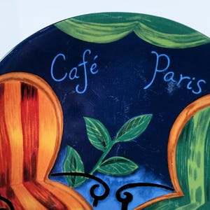 Furio Café salad plates display colorful empty chairs sitting at a French Cafe scene with two colorful and a cafe table
