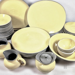 May include: A set of yellow and gray ceramic dinnerware, including plates, bowls, cups, and a creamer and sugar set.