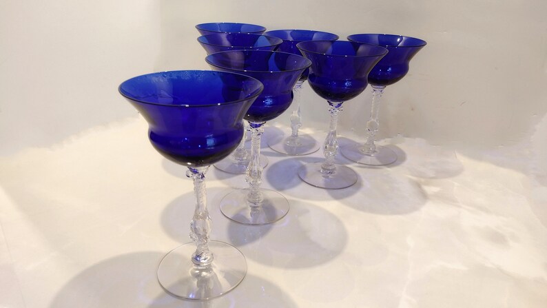 MSet of 7 Antique Cobalt Royal Blue 3126 Cambridge Glass Champagne / Tall Sherbet Stemware.  Beautiful, clear cobalt blue art deco style angular flare top on a bulbous, bulging bowl with graceful foliated clear glass tall stems.ay include: Set of six cobalt blue stemmed glasses with clear glass stems and bases. The glasses have a wide bowl and a delicate, twisted stem.