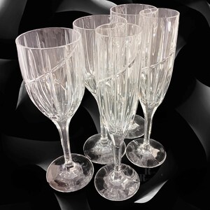 Vintage Mikasa Uptown clear heavy cut crytal stemware. This 5 piece set consists of three 9 inch water goblets and two 9 1/2 inch fluted champagne glasses. The bowls are vertically cut and polished from the rim to the stem and one horizontal spiral around the bowl. The tall slender stems are six-sided and curver gracerully into thesix-segmented foot.