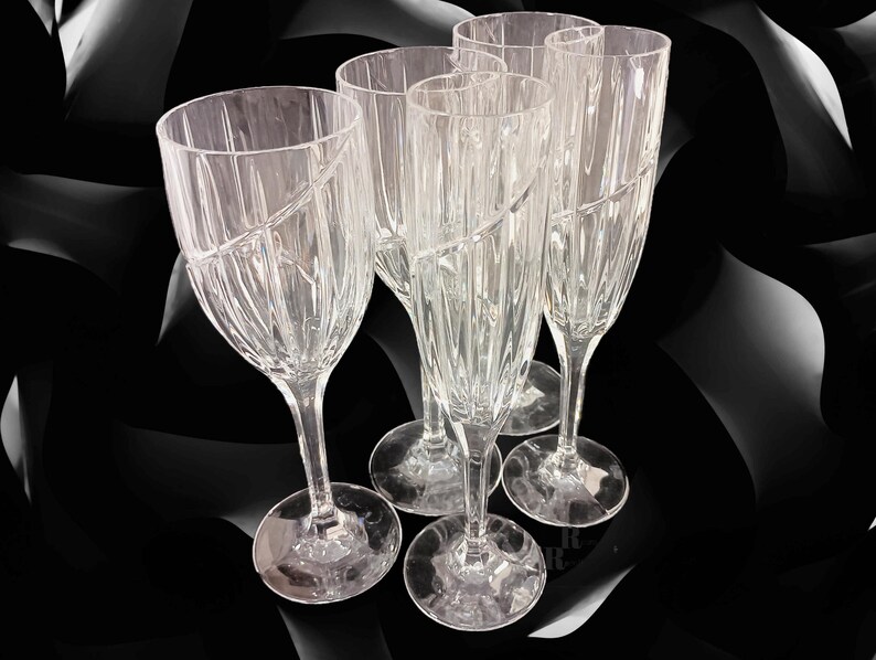 Vintage Mikasa Uptown clear heavy cut crytal stemware. This 5 piece set consists of three 9 inch water goblets and two 9 1/2 inch fluted champagne glasses. The bowls are vertically cut and polished from the rim to the stem and one horizontal spiral around the bowl. The tall slender stems are six-sided and curver gracerully into thesix-segmented foot.